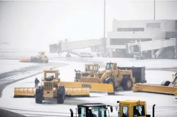  ?? SCOTT EISEN/GETTY IMAGES ?? Crews at Boston’s Logan Internatio­nal Airport plow snow from the runways as a major storm blows through on Thursday.