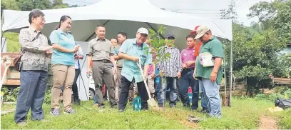  ??  ?? PULIHARA: Fredolin menanam pokok sebagai simbolik kepada pemulihara­an hutan kawasan tadahan air Babagon.