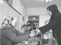  ?? EMRAH GUREL EMRAH GUREL, AP ?? A voter takes a ballot from a member of an electoral committee, left, in Istanbul on Sunday. With 99% of the ballots counted, 51.4% favored the referendum and 48.6% opposed.