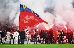  ??  ?? Red sea: Lyon fans and players celebratin­g their victory over Marseille at the Groupama Stadium on Sunday. Lyon won 2- 0. —Reuters