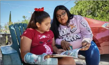  ?? DA’SHAUNAE MARISA FOR CALMATTERS ?? Elizabeth Lomeli reads to her daughter, Gisselle, at their home in Pacoima on April 23.