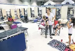  ??  ?? Heather Flores holds her one-year-old son, Bronx Flores, while getting settled into a shelter with her other children Jaydin (centre) and Paris (right) at the Lyman High School in Longwood, Florida, yesterday.