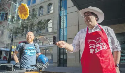  ?? ARYN TOOMBS/CALGARY HERALD ?? Calgary Herald reporter Trevor Howell, left, watches as Mayor Naheed Nenshi flips pancakes at the sixth annual First Flip in Calgary. Federal party leaders are expected at the Calgary Stampede to meet voters as the unofficial election season kicks off.