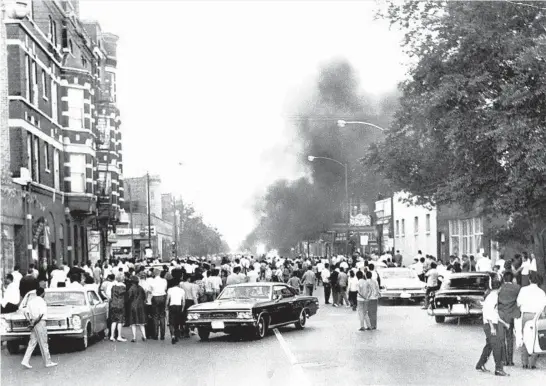  ?? JAMES MAYO/CHICAGO TRIBUNE ?? A crowd surrounds a burning squad car June 12, 1966, in Humboldt Park in what is considered the first eruption of mass unrest on the U.S. mainland by Puerto Ricans.