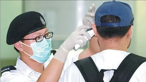  ?? HUO YAN / CHINA DAILY ?? A paramedic checks a man’s health during the 2003 outbreak of SARS in Hong Kong.