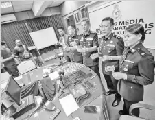  ??  ?? Abang Ahmad (third right) shows the black satchel which contained the drugs. He is flanked by his deputies Supt Abang Junaidi Abang Anuar (left) and Supt Ismail Mahmood.