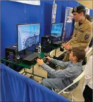  ?? RECORDER PHOTO BY CHARLES WHISNAND ?? Portervill­e Military Academy cadet Esteban Gutierrez instructs a student in using PMA’S flight simulator at Thursday’s Pathways Expo.