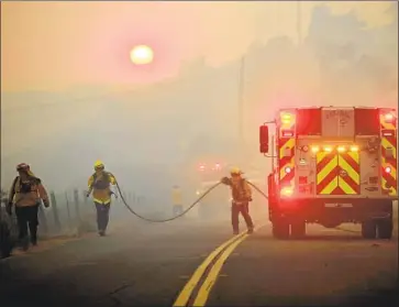  ?? Luis Sinco Los Angeles Times ?? SUNDOWNER WINDS racing down the slopes of the Santa Ynez Mountains toward the sea have helped drive the Alisal fire to more than 13,000 acres. Firefighte­rs worked Tuesday along the 101 Freeway near Goleta.