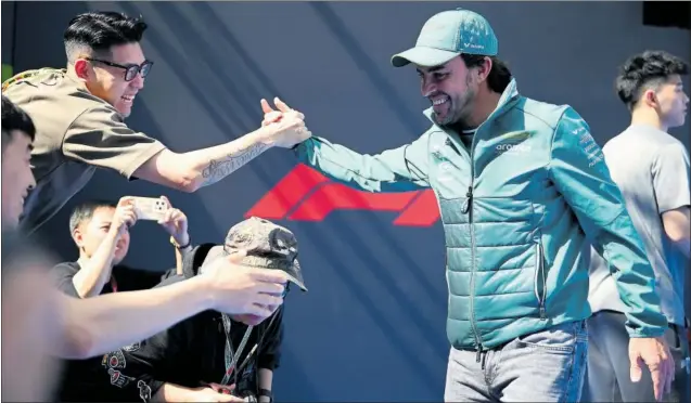  ?? ?? Fernando Alonso saluda a Liu Guanyu en una pista de baloncesto situada en el ‘paddock’ del circuito de Shanghái en el que se celebra el GP de China de F1 este fin de semana.