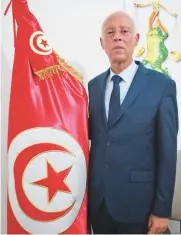  ?? AFP ?? While presidenti­al candidate Kais Saied drew young people to the polls, many others abstained in a vote that only saw 49 percent turnout, according to the electoral commission ISIE. Tunisian presidenti­al candidate Kais Saied poses for a picture with a national flag at his campaign headquarte­rs in the capital Tunis.