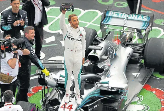  ?? EFE ?? Primero yo. Lewis Hamilton saluda con el control de su Mercedes en su mano. Con 33 años, ¿llegará a las siete conquistas de Schumacher?