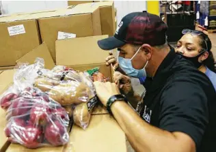  ??  ?? San Antonio Food Bank Warehouse Manager David Carvajal inspects a box of produce from the CRE8AD8/USDA contract.