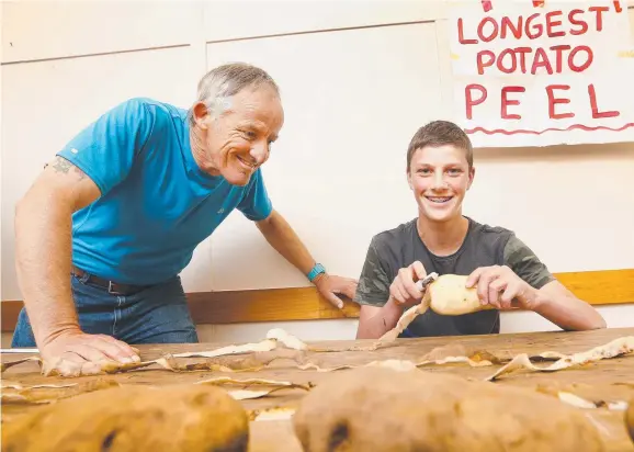  ?? Pictures: CHRIS KIDD ?? EYES PEELED: Ralph Bosch and Brayden Lynd, 14, try the longest potato peel competitio­n at the Gunns Plains Potato Festival.