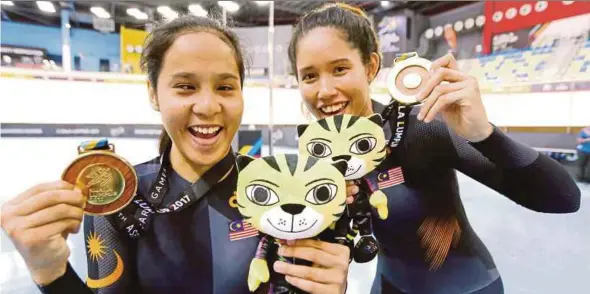  ?? PIC BY IQMAL HAQIM ROSMAN ?? Nur Azlia Syafinaz Mohd Zais (left) and pilot rider Noraidilli­na Adilla J. Sam celebrate after winning the 3km pursuit B class (blind/visually impaired) at the National Velodrome in Nilai yesterday.