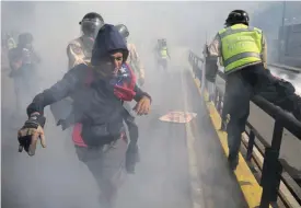  ?? FOTO: TT-AP/FERNANDO LLANO ?? En demonstran­t flyr undan regeringss­tyrkor under en protest mot president Nicolás Maduro i Caracas.
