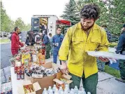  ?? [PHOTO BY ANNA STONEHOUSE, THE ASPEN TIMES VIA AP] ?? Roberto Solares, of the Nyssa, Ore., West Coast Restoratio­n fire crew, grabs breakfast from the Salvation Army truck Friday morning before heading out onto the line fighting the Lake Christine wildfire in El Jebel, Colo.