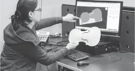  ??  ?? Luthier Charline Dequincey examines part of a prototype of a 3D-printed violin. 3D-printed designs can be easily customized and changed without a great increase in cost. Eight 3D-printed stringed instrument­s will be included in Ottawa Symphony...