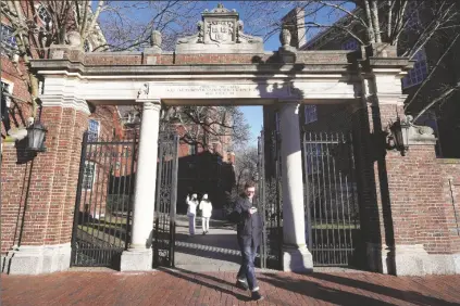  ?? STEVEN SENNE/AP ?? A PASSER-BY WALKS THROUGH A GATE to the Harvard University campus on Jan. 2 in Cambridge, Mass.