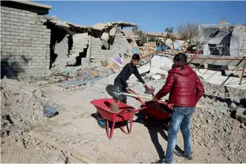  ?? — AFP ?? Shabak boys clear rubble around their house in the village of Baz Gerkan east of Mosul