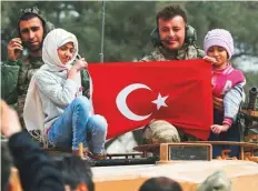  ?? AP ?? Turkish soldiers atop a tank pose for pictures with Syrian children holding a Turkish flag in Afrin.