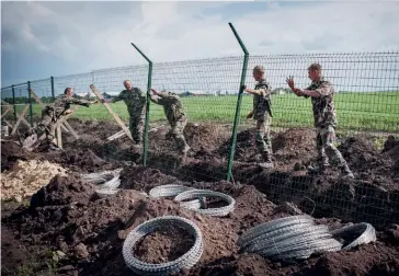  ?? (© E. Kryzhanivs­kyi/ Shuttersto­ck) ?? Photo ci-dessus : En 2015, des soldats ukrainiens installent une clôture à la frontière avec la Russie dans la région de Kharkov, dans le Nord-Est de l’Ukraine, à la suite de l’annexion de la Crimée par Moscou. Début 2020, le président ukrainien V. Zelensky a émis l’idée de construire un mur repoussant le Donbass séparatist­e en dehors de l’Ukraine, pour en faire « un autre territoire qui ne serait plus considéré comme le nôtre, (…) juste une zone non reconnue par la communauté internatio­nale et occupée par des miliciens ».