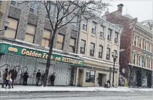  ?? PAUL WILSON SPECIAL TO THE HAMILTON SPECTATOR ?? Left: Commuters wait for the bus in front of the long-deserted Golden Fortune at 18 John St. N. near King.