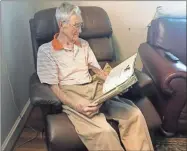  ?? Doug Walker ?? Ed Edmondson, who first attended Camp Sidney Dew in 1940 and has volunteere­d at the camp virtually his entire adult life, looks back through a scrap book of memories related to the Boy Scout camp in an easy chair at his home.