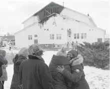  ??  ?? Community members look on as firefighte­rs extinguish hot spots Wednesday at St. Thomas Baptist Church in North Preston, N.S.