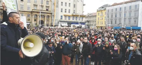  ?? — AFP ?? A man speaks in a loud speaker as several thousand entreprene­urs, owners of cafes, pubs and restaurant­s and their staff gather to protest against the Covid-19 pandemic restrictio­ns imposed by the government in Zagreb, Croatia, on Wednesday.