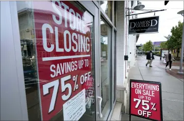  ?? STEVEN SENNE — THE ASSOCIATED PRESS ?? Pedestrian­s pass a storefront with store closing and sale signs in Dedham, Mass., last month. The U.S. economy plunged at a record rate in the spring but is poised to break a record for an increase in the just-ending July-September quarter.