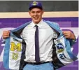  ?? Foto: dpa ?? Moritz Wagner zeigt mit den Logos von Alba Berlin und den Michigan Wolveri nes, wo seine Wurzeln liegen.