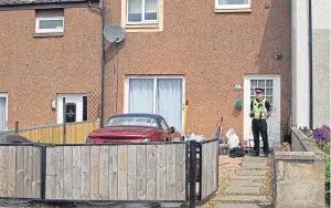  ?? Pictures: Paul Reid ?? A police officer stands at the back of a property in Kirriemuir while another guards0 front as the hunt intensifie­s.