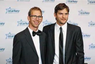  ?? ADAM BETTCHER/ GETTY IMAGES FOR STARKEY HEARING FOUNDATION/TNS ?? Michael Kutcher (left) and brother Ashton Kutcher walk the red carpet before the 2013 Starkey Hearing Foundation’s “So the World May Hear” Awards Gala on July 28, 2013, in St. Paul, Minnesota.