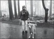  ?? AP/ KATHLEEN RONAYNE ?? Eric Darling and his dog Wyatt are part of a search team from Orange County in Southern California among several teams conducting a second search Friday of a mobile home park after the deadly Camp Fire in Paradise, Calif. The second search was necessary because of reports of missing people whose last known address was at the mobile home park. The teams look for clues that may indicate someone couldn’t get out, such as a car in the driveway or a wheelchair ramp.