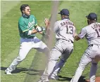  ?? STAN SZETO/ USA TODAY SPORTS ?? Athletics outfielder Ramon Laureano, left, is restrained by Astros catcher Dustin Garneau as he charges the Houston dugout after being hit by a pitch.