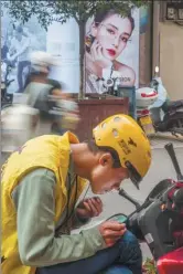  ??  ?? A food delivery rider takes advantage of his leisure time to groom his beard in Jiang’an county, Sichuan province.