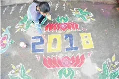  ??  ?? A woman applies coloured powder to a ‘rangoli’, a Hindu ritual design, to usher in the New Year in front of a home in Hyderabad. — AFP photo