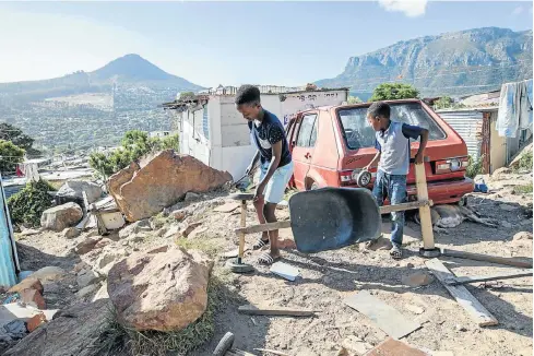  ?? Pictures: Anton Crone ?? GARAGE WITH A VIEW Livakele Dingwayo repairs his go-kart with the help of Amvuyele Maphempeni outside his home on the slopes of Imizamo Yethu.