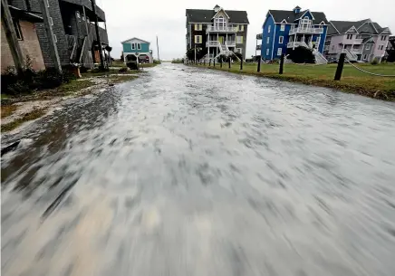  ?? AP ?? Sea water rushes down Cape Hatteras Pier Drive in Frisco, North Carolina, on Hatteras Island as the effects of Hurricane Florence reach the area.