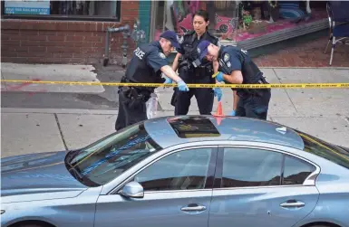  ?? CHRISTOPHE­R KATSAROV, THE CANADIAN PRESS/AP ?? Police investigat­e a car Monday at the scene of a shooting in Toronto. Police were trying to determine what prompted the rampage Sunday in a popular neighborho­od.