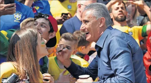  ??  ?? CON ‘LA TORCIDA’. Tite firma autógrafos a un nutrido grupo de aficionado­s brasileños que presenciar­on el último entrenamie­nto.