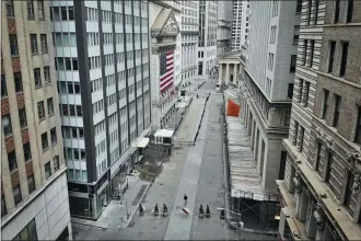  ?? JOHN MINCHILLO — THE ASSOCIATED PRESS FILE ?? A lone pedestrian wearing a protective mask walks past the New York Stock Exchange as coronaviru­s concerns empty a typically bustling downtown area in New York over the weekend. Stocks around the world swung lower Monday even after the Federal Reserve announced a tidal wave of support for lending markets.