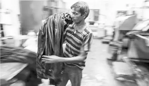  ??  ?? A worker unloads jeans from a fabric dyeing machine at a factory in the Mundargi Industrial Area of Ballari, Karnataka, India, on May 16.