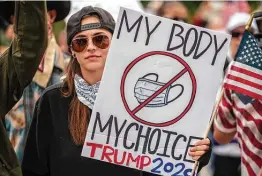  ?? Getty Images file photo ?? A demonstrat­or at an April rally at the Capitol in Austin holds a sign protesting authoritie­s’ recommenda­tion to wear a mask to slow the spread of COVID-19.
Jaime Caldera, originally from San Antonio, sells face masks in Los Angeles. One national survey last month reported that 73 percent of selfidenti­fied Democrats were wearing masks; for Republican­s, the total was 59 percent.