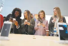  ?? Justin Sullivan, Getty Images file ?? Customers inspect the iPhone X at an Apple store in Palo Alto, Calif., in November 2017.