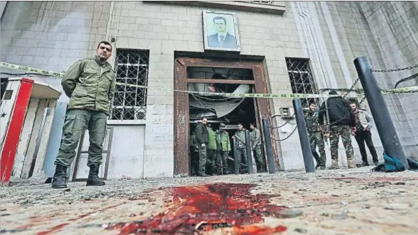  ?? LOUAI BESHARA / AFP ?? La entrada del Palacio de Justicia de Damasco, con el retrato del presidente Bashar el Asad, tras el atentado suicida