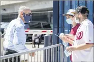  ?? ANDREW HARNIK — THE ASSOCIATED PRESS ?? MLB Commission­er Rob Manfred, left, speaks with fans as he arrives at Nationals Park for the New York Yankees and the Washington Nationals opening day baseball game, Thursday, July 23, 2020, in Washington.