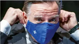  ?? CP PHOTO PAUL CHIASSON ?? Quebec Premier Francois Legault slips on a mask after speaking in Montreal on Tuesday.