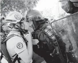  ?? LEWIS JOLY/AP ?? Police officers in riot gear confront a first aid volunteer Sunday at a May Day demonstrat­ion in Paris. Protesters demanded that government do more to help workers.