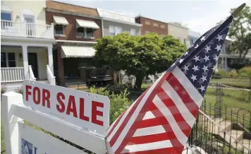  ?? — Reuters ?? A US flag decorates a for-sale sign at a home in the Capitol Hill neighbourh­ood of Washington.